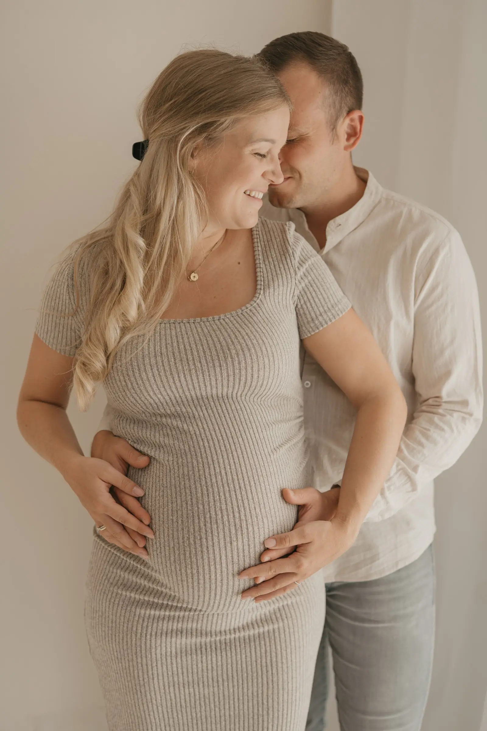 Paar hält gemeinsam den Babybauch im Studio