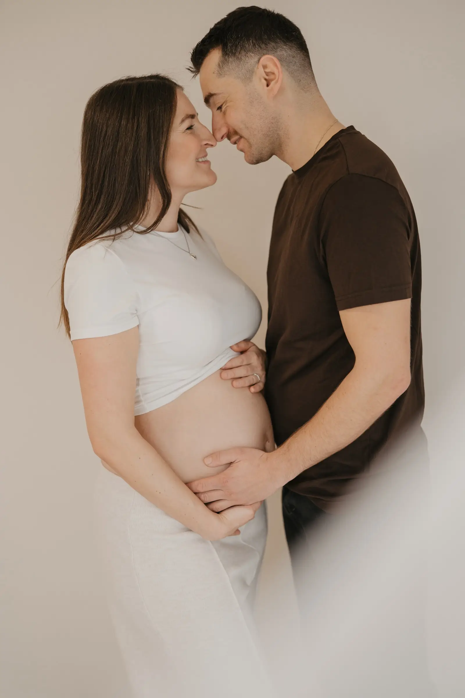 Paar schaut sich an, sie hält den Babybauch im weißen Top