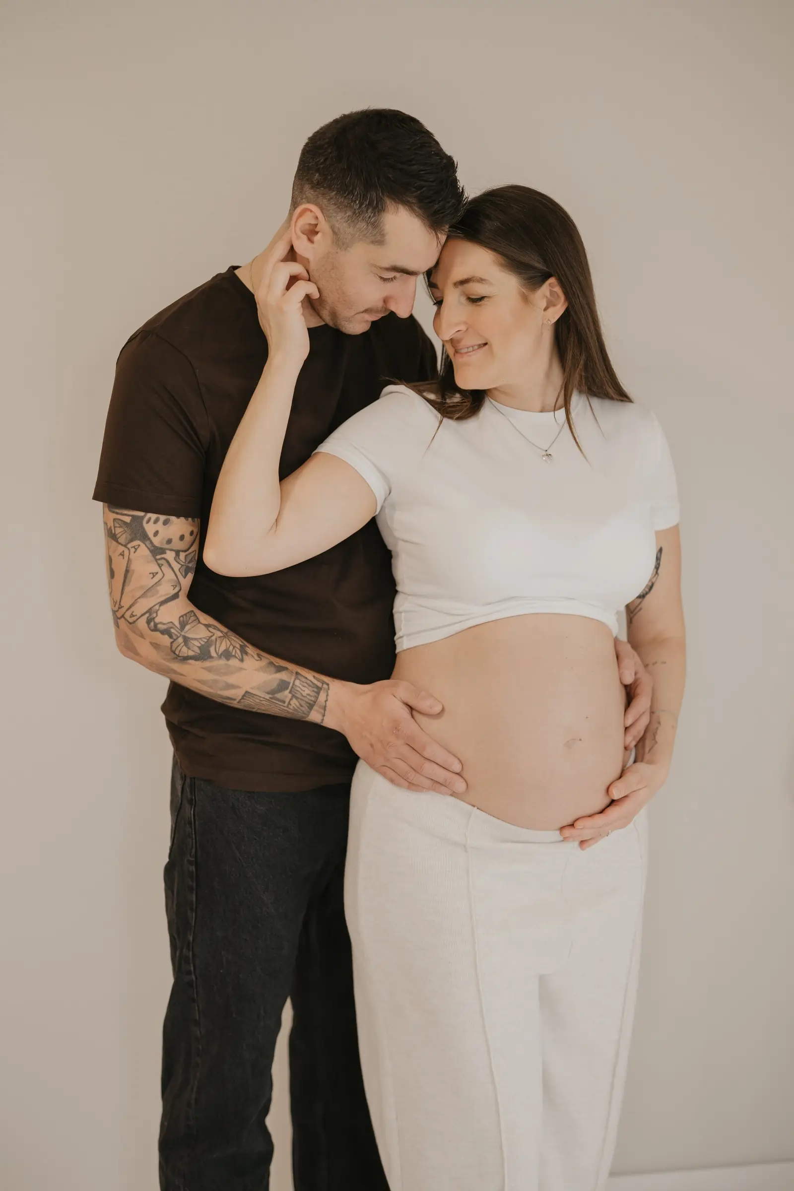 Paar umarmt sich, Hände auf dem Babybauch im Studio