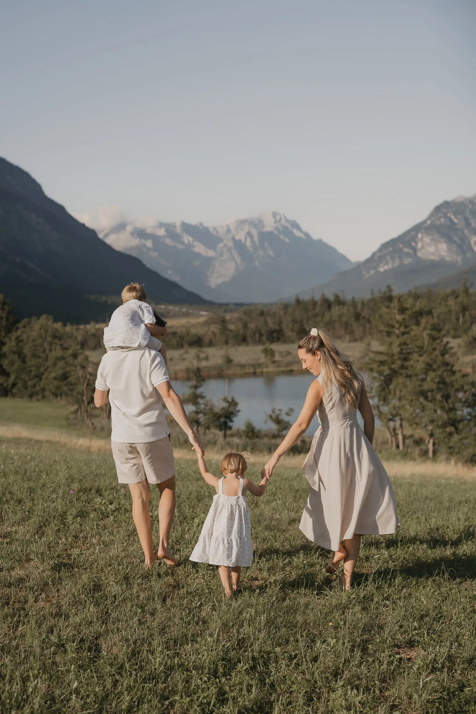 Familie geht Hand in Hand über eine Wiese vor Bergpanorama