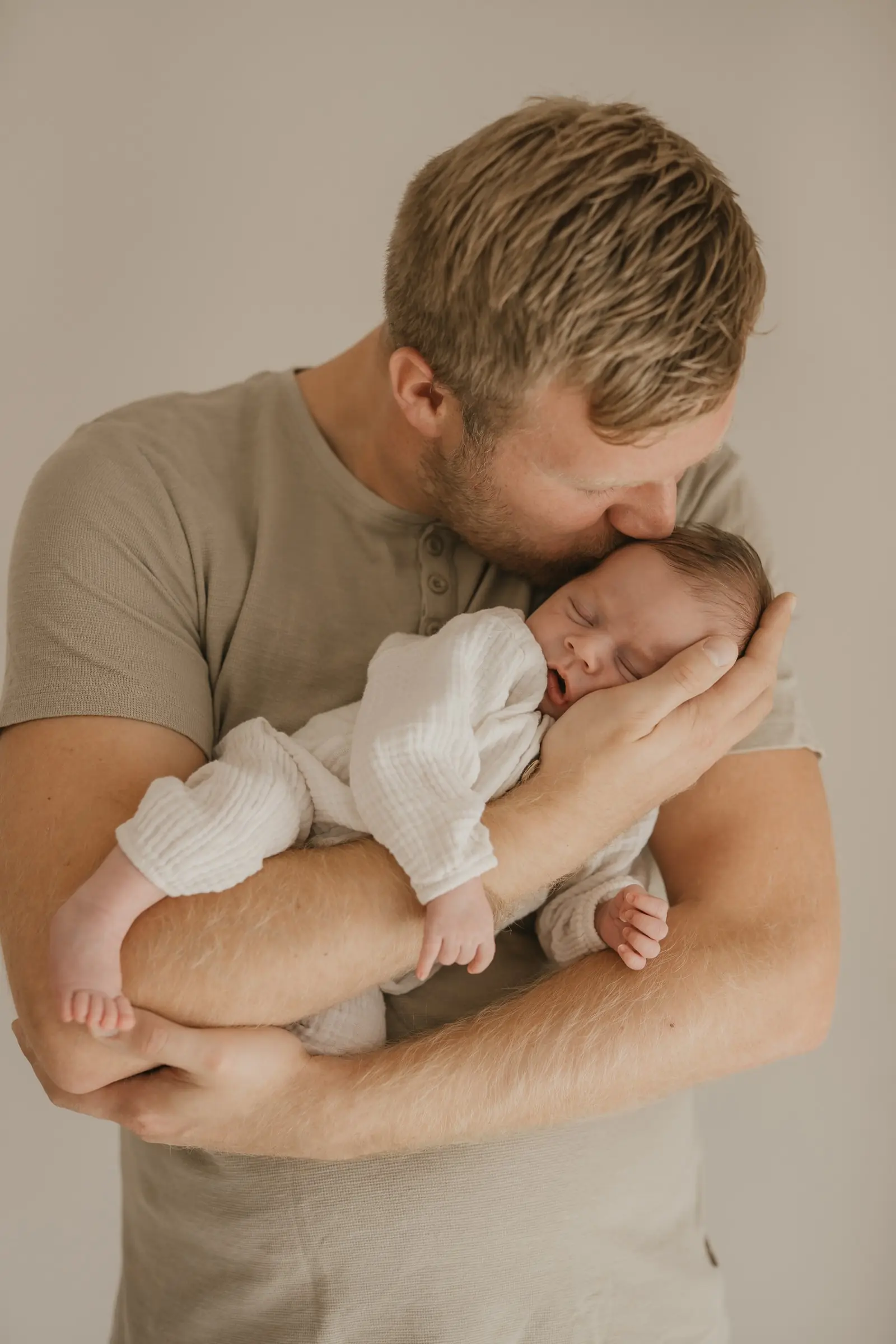 Vater hält sein schlafendes Neugeborenes eng im Arm
