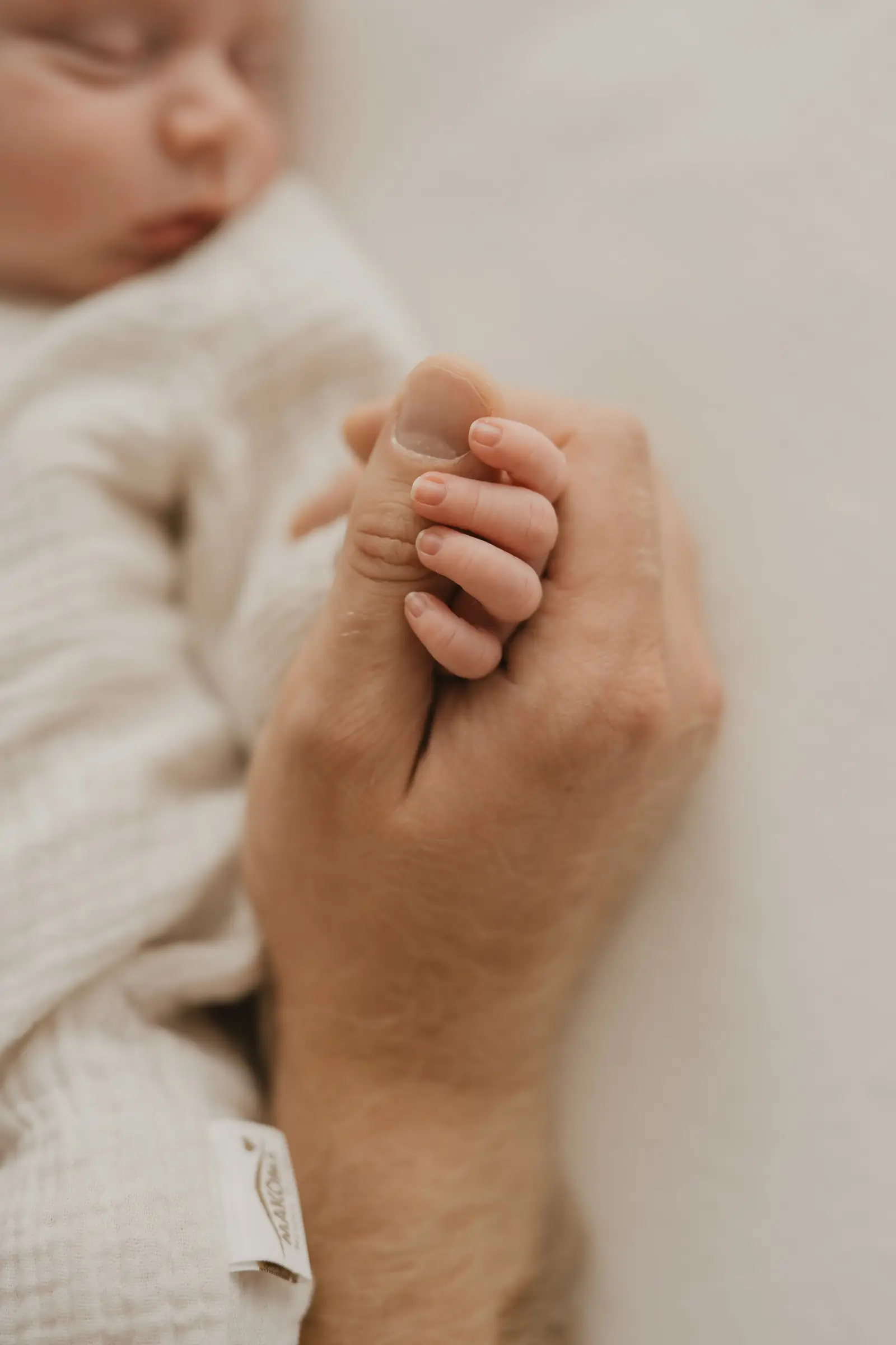 Vaterhand hält die Hand des Neugeborenen