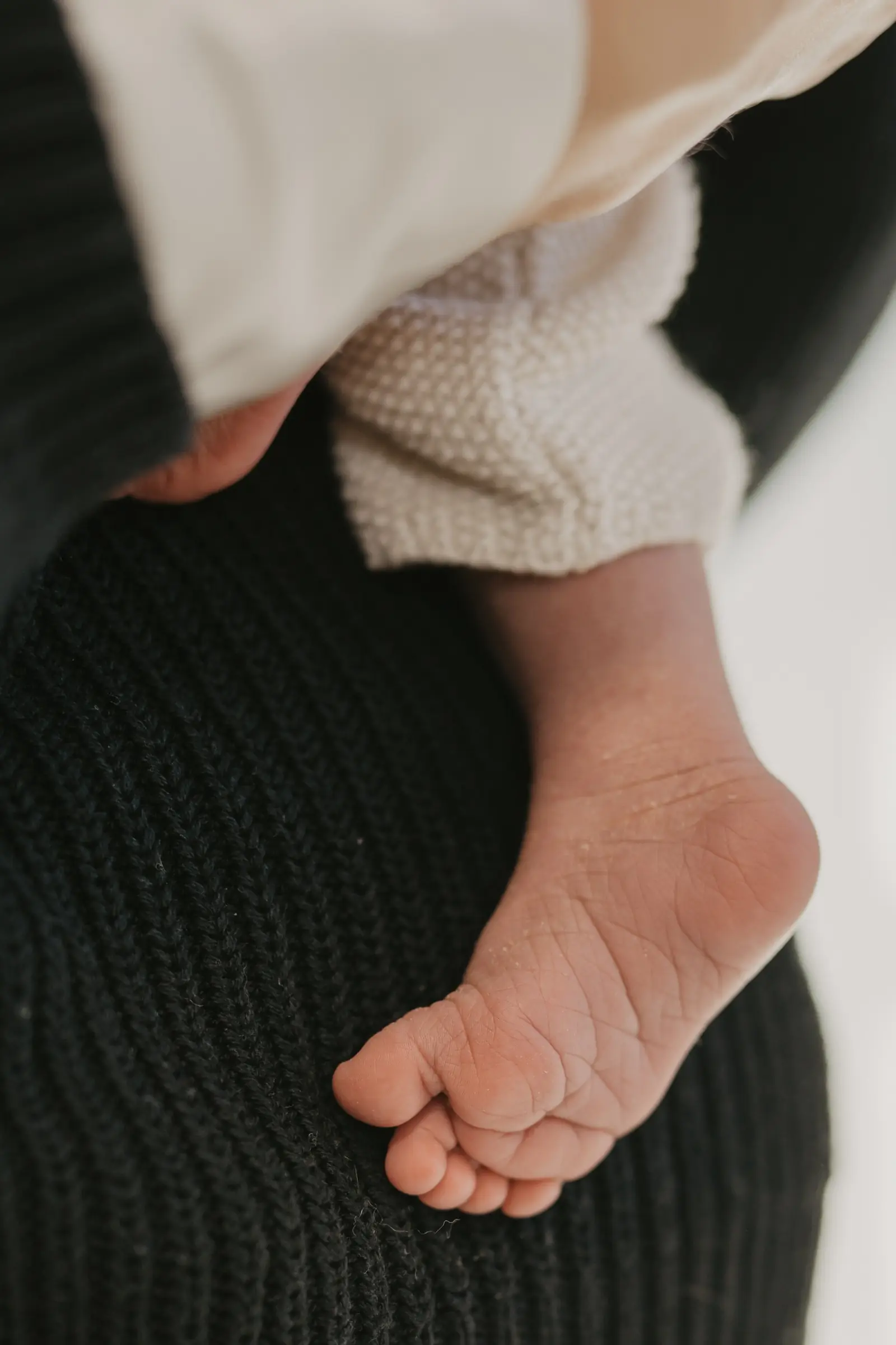 Babyfüße auf dunklem Strickstoff, Detailaufnahme